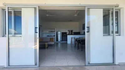 an open sliding glass door in a living room with a kitchen at Endless Horizon Apartments in Las Terrenas