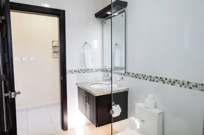 a bathroom with a sink and a mirror and a toilet at Newly built 2 bedroom 2 bath private pool villa! in Sosúa
