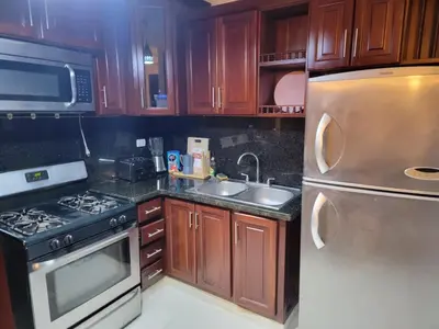 a kitchen with wooden cabinets and a stainless steel refrigerator at Apartamento Confortable Moderno Minimalista in Ciruelitos Arriba