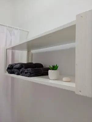 a white shelf with a pile of clothes on it at Quédate Aquí También in Las Galeras