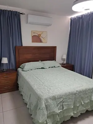 a bedroom with a large bed with blue curtains at Torre san geronimo 1109 apartamento 10-06 in Santo Domingo