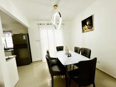 a dining room with a table and chairs and a refrigerator at Ideal space for the family in Boca Chica