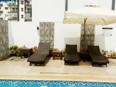 two chairs and an umbrella next to a swimming pool at Ideal space for the family in Boca Chica