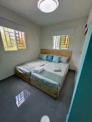 a large bed in a room with two windows at Villa yaya 1 in Boca Chica