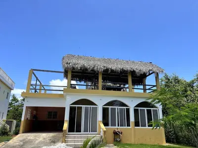 a large house with a thatched roof at Casa La Loma En Las Galeras in Colorado