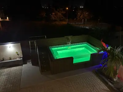 a hot tub with a green light in a backyard at night at Villa Sol Odalis in Jarabacoa