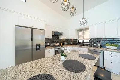 a kitchen with white cabinets and a granite counter top at Peace Design Exclusivity in Sosúa