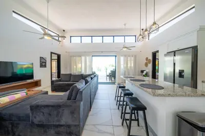 a living room with a couch and a bar with stools at Peace Design Exclusivity in Sosúa