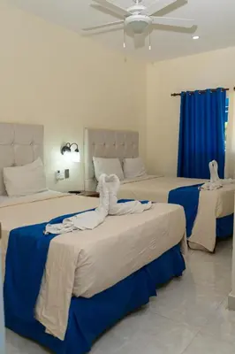 a bedroom with two beds with blue and white sheets at Hotel cotubanama