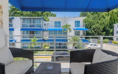 a view of a building from a balcony with chairs and a table at Resort Villas | 2 hab con piscina y playa in Juan Dolio
