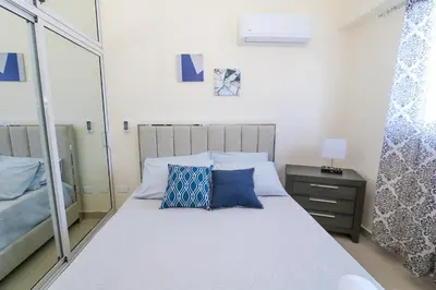 a bedroom with a bed with blue pillows and a mirror at Edificio Amber in San Cristóbal