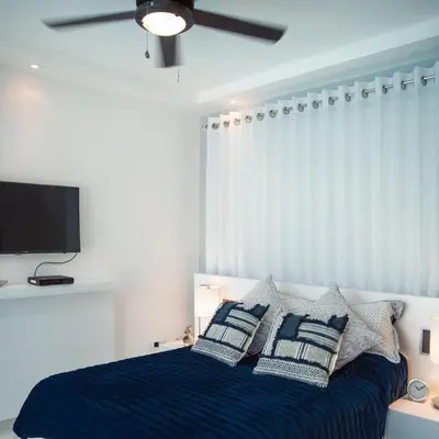 a bedroom with a bed with pillows and a ceiling fan at Crown 1 in Puerto Plata