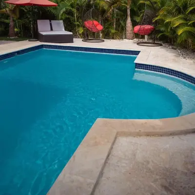 a swimming pool with blue water and red umbrellas at Crown 1 in Puerto Plata