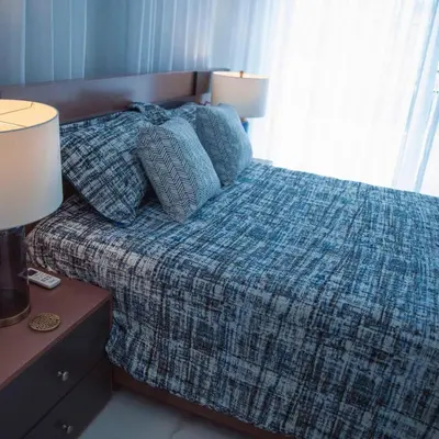 a bedroom with a bed with a plaid blanket and two lamps at Crown 1 in Puerto Plata