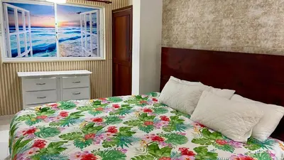 a bedroom with a bed with a floral bedspread and a window at Sea Near and Beach a few minutes walking Top Location by RHV Living in San Felipe de Puerto Plata