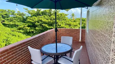 a table and chairs with an umbrella on a balcony at Sea Near and Beach a few minutes walking Top Location by RHV Living in San Felipe de Puerto Plata