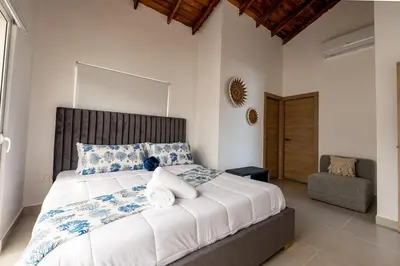 a bedroom with a large bed and a chair at Armonía Las Terrenas in Las Terrenas