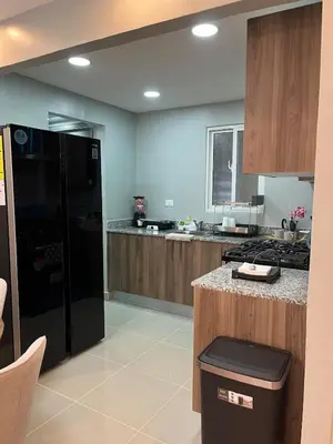 a kitchen with a black refrigerator and wooden cabinets at Moderno Apartamento Boca Chica, 5 minutos del Aeropuerto in La Caleta