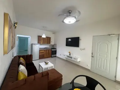 a living room with a brown couch and a kitchen at Paisible et confo in Boca Chica