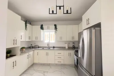 a kitchen with white cabinets and a stainless steel refrigerator at Elegante Casa Estrella Marina 117 Pool BBQ in La Romana