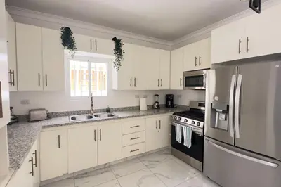 a white kitchen with white cabinets and black appliances at Elegante Casa Estrella Marina 117 Pool BBQ in La Romana