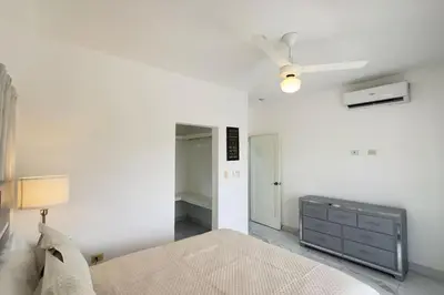 a white bedroom with a bed and a ceiling fan at Elegante Casa Estrella Marina 117 Pool BBQ in La Romana