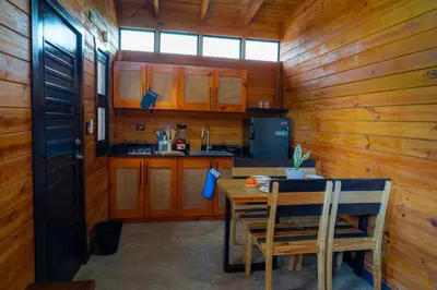 a kitchen with a table and a wooden wall at Villa Dulce Refugio in Cabrera