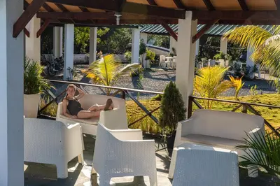 a woman laying on a chair on a patio at LAS PALMAS 2 VILLA 20 personnes pool in Palmar de Ocoa