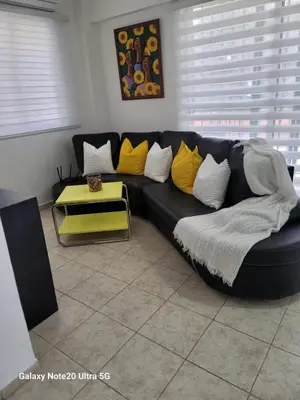 a black couch with yellow pillows in a living room at Apartamento dos dormitorios en la zona colonial in Santo Domingo