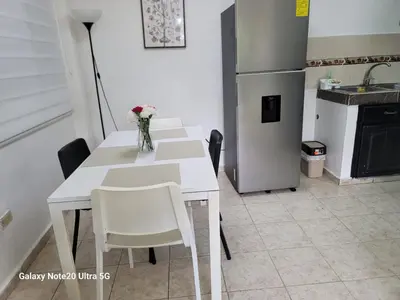 a kitchen with a white table with chairs and a refrigerator at Apartamento dos dormitorios en la zona colonial in Santo Domingo