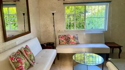 a living room with a white couch and two windows at A Few Steps to Malecon and Sunny Beaches in San Felipe de Puerto Plata