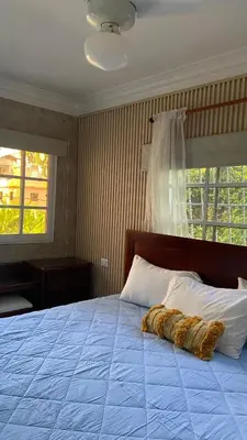 a bedroom with a large bed with a blue comforter and two windows at A Few Steps to Malecon and Sunny Beaches in San Felipe de Puerto Plata