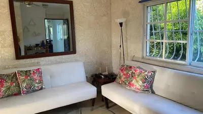 a living room with two white couches and a mirror at A Few Steps to Malecon and Sunny Beaches in San Felipe de Puerto Plata