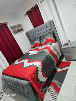 a bed with a red and black blanket on it at Peaceful Cottage in Santiago de los Caballeros
