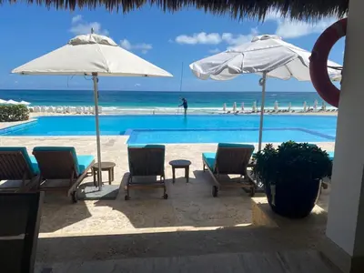 a pool with chairs and umbrellas and the ocean at Beach Golf penthouse Arena Gorda Beach P C in Punta Cana