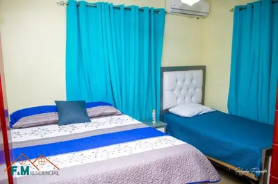 a bedroom with two beds and blue curtains at Remanso de Paz in Pedernales