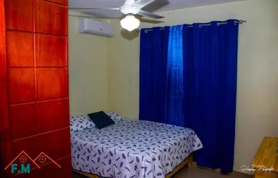 a bedroom with a bed with blue curtains and a ceiling fan at Remanso de Paz in Pedernales