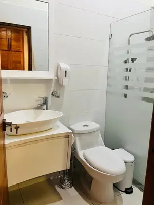 a white bathroom with a toilet and a sink at Brisas de Valle in Jarabacoa