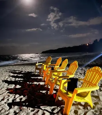 a row of lawn chairs on the beach at night at Playa Rene RD in San Felipe de Puerto Plata