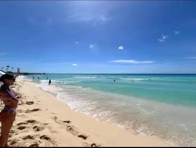 a woman standing on a beach with people in the ocean at Estrella Izha 204 in La Laguna