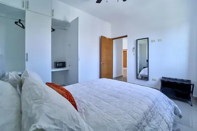 a bedroom with a white bed and a mirror at Cozy Nest in La Romana