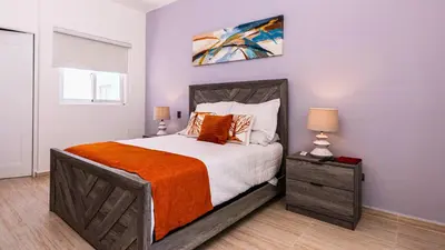 a bedroom with a large bed with an orange blanket at Maple Beach Residences Punta Cana in Punta Cana