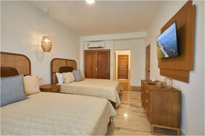 a hotel room with two beds and a flat screen tv at Apartamento Moderno en Playa Dorada Piscina & Playa in Puerto Plata