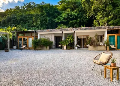 a house with a gravel courtyard with chairs and trees at Residencia AKKMA - Autentico y dominicano con AC in Las Terrenas