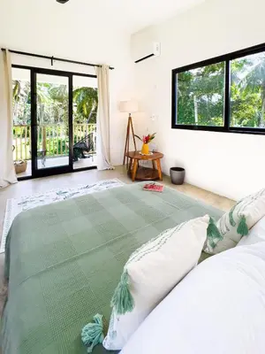a bedroom with a large green bed with windows at Jungle Tiny House in El Valle