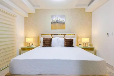 a bedroom with a large white bed with two lamps at Cozy 2BR Condo, Spectacular Rooftop in Santo Domingo