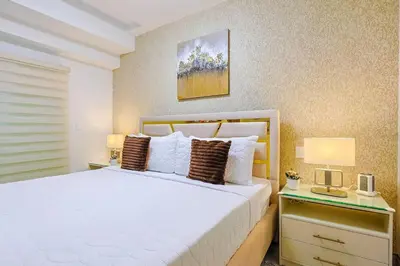 a bedroom with a large white bed with two lamps at Cozy 2BR Condo, Spectacular Rooftop in Santo Domingo
