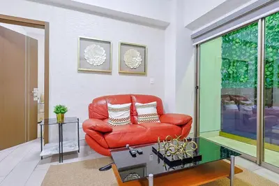 a red couch in a living room with a window at Cozy 2BR Condo, Spectacular Rooftop in Santo Domingo