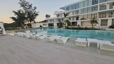 a swimming pool with white chairs and a building at Mireyas Sweet Escape with private Jacuzzi in Las Terrenas