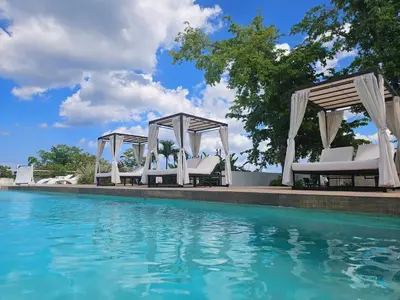 a group of white chairs next to a swimming pool at Mireyas Sweet Escape with private Jacuzzi in Las Terrenas
